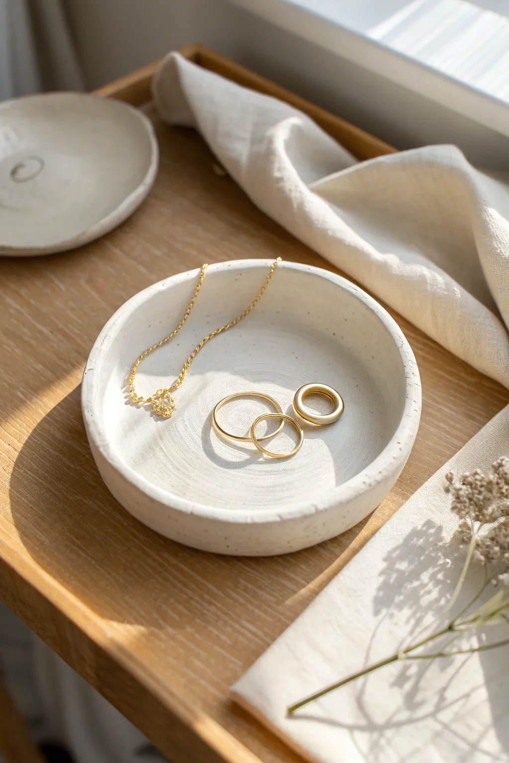 Classic round air dry clay trinket dish with a matte finish, styled with rings and a necklace.