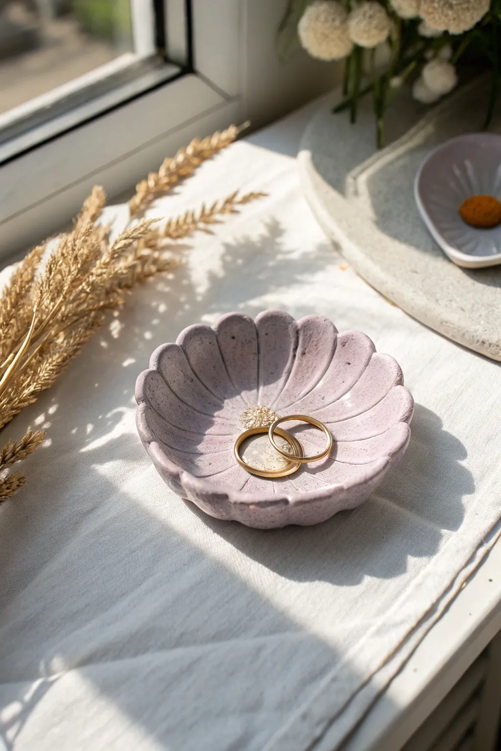 Matte pastel daisy trinket dish in lavender, minimal styling with rings and soft daylight.
