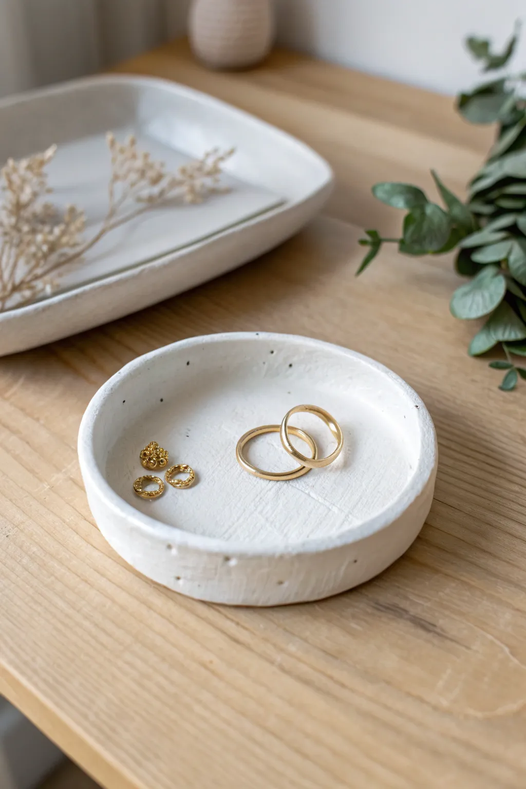 Classic white air dry clay trinket tray with a soft rim, styled with rings on light oak.