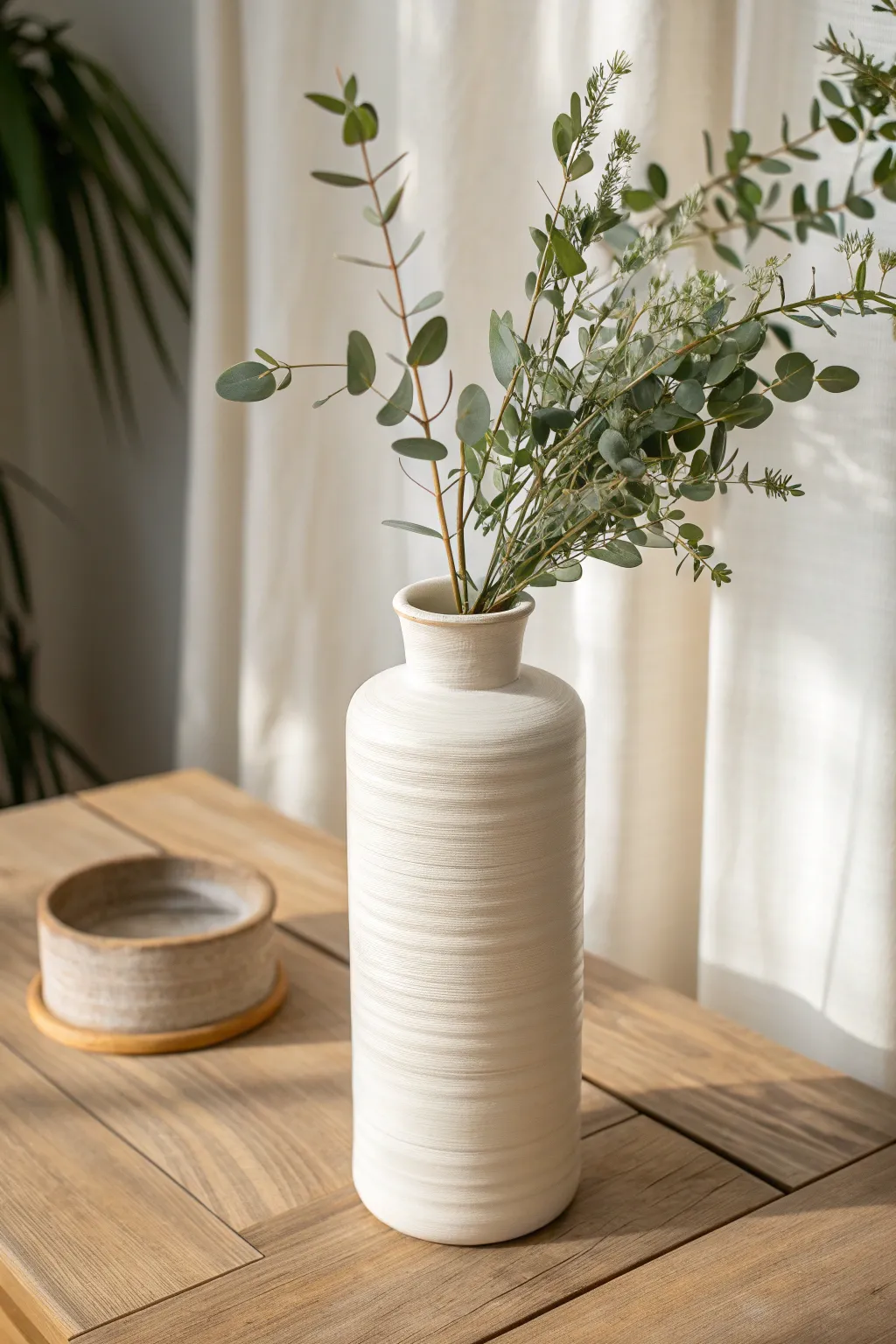 Classic wheel-thrown cylinder vase in satin white, styled with eucalyptus for a calm modern look