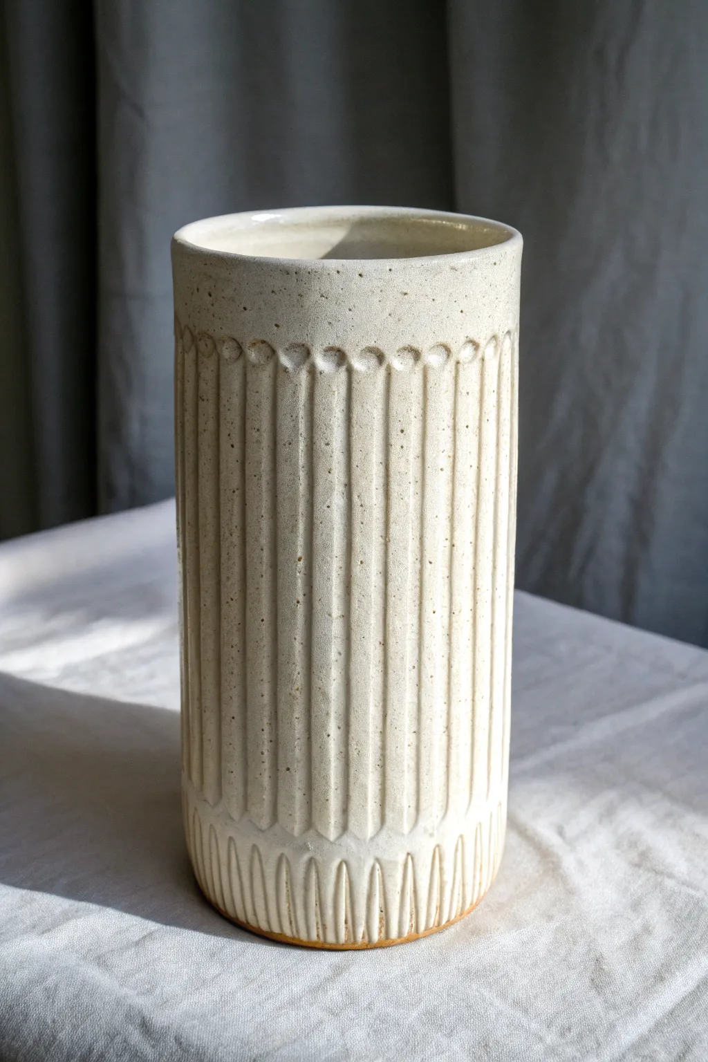Simple carved lines and glossy glaze breaks create effortless texture on a minimalist vase.