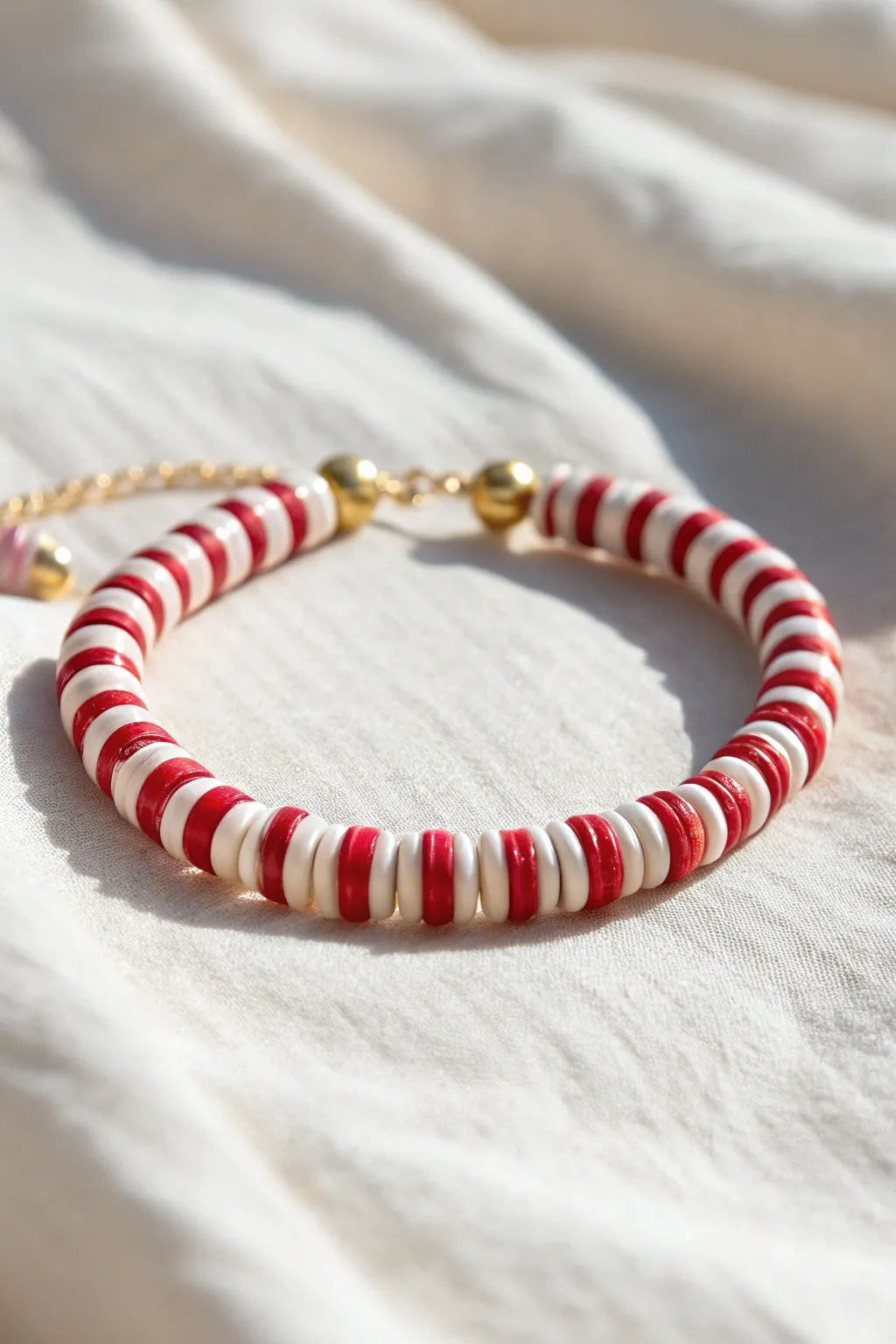 Classic candy cane clay bead bracelet with red and white stripes and tiny gold accents.