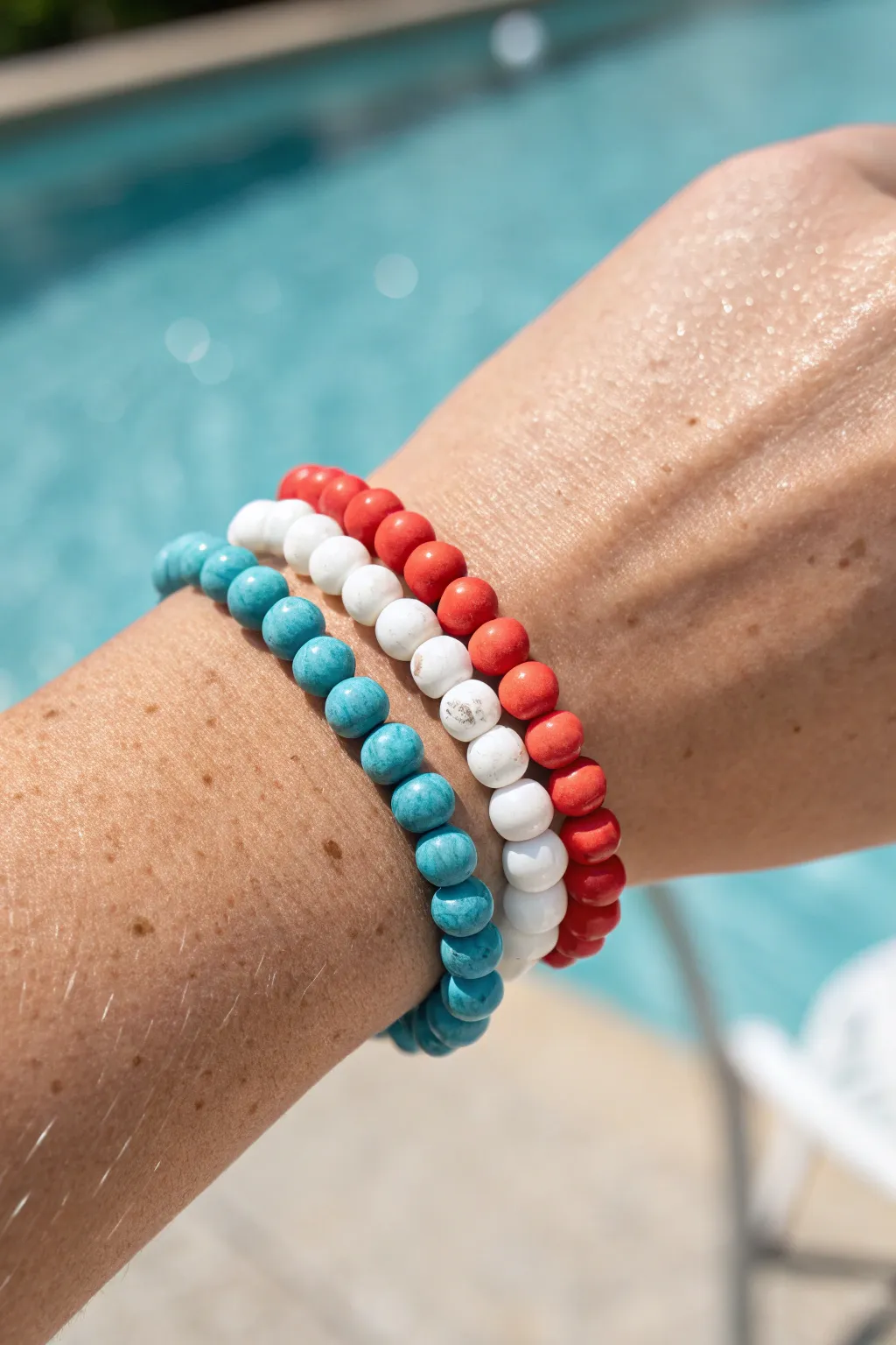 Classic summer clay bead stack in turquoise, coral, and white, sunlit and poolside.