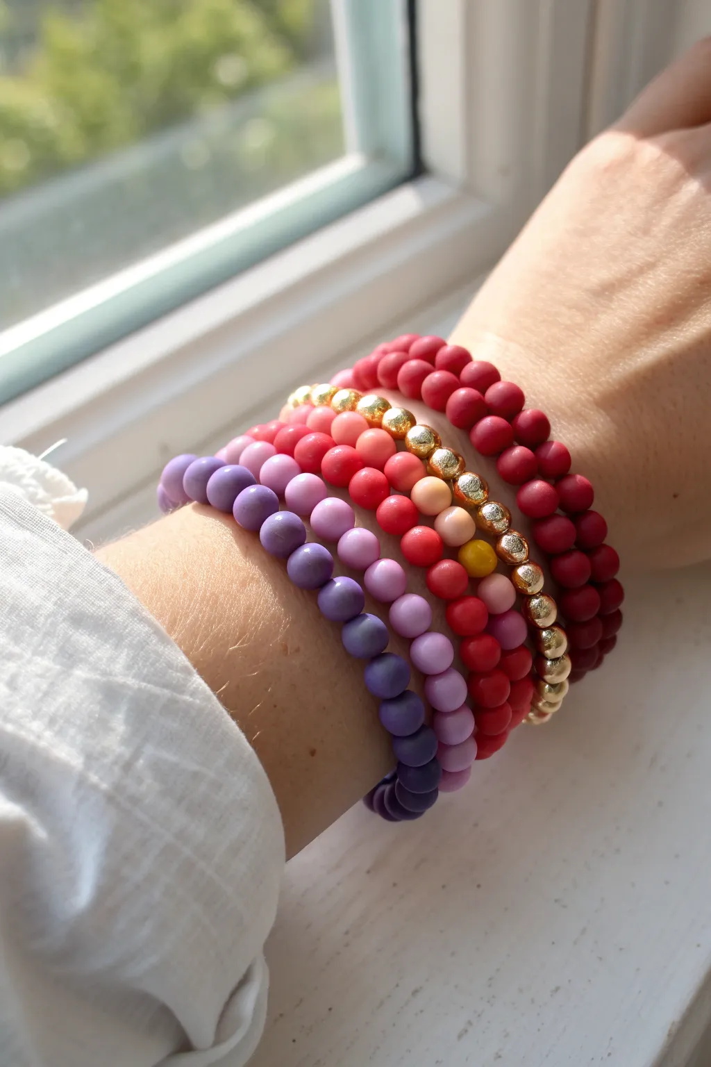 Classic rainbow clay bead bracelet stack with delicate gold spacers in bright, summery light.