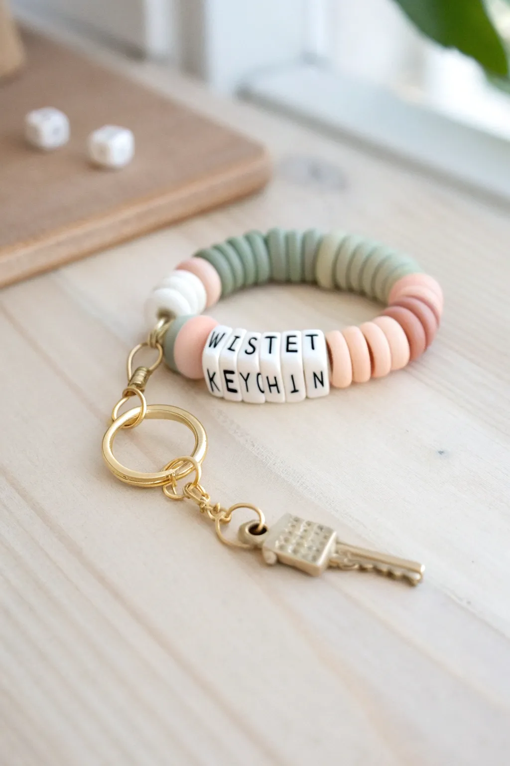 Soft neutral heishi bead wristlet keychain with centered name beads, styled with keys for scale.