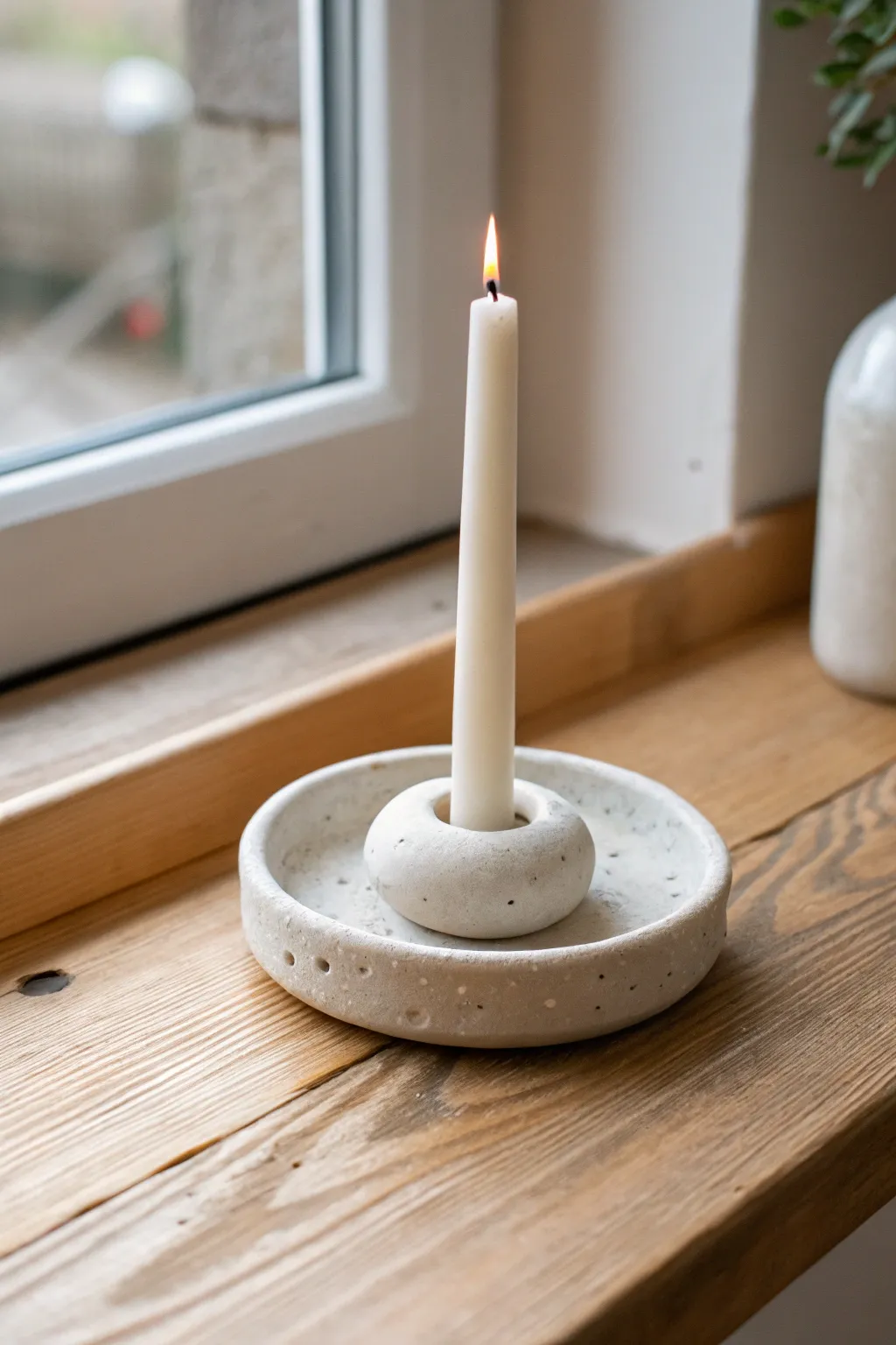 Minimal clay taper ring holder on light wood, soft cozy light and clean Scandinavian calm