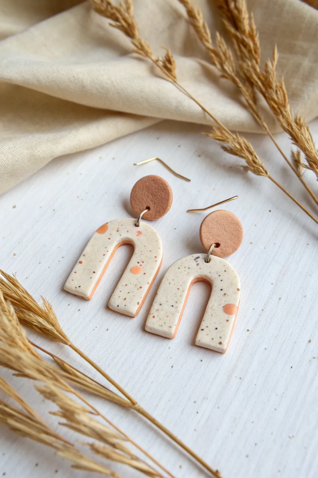 Minimal matte clay arch dangles on linen for a soft modern look with crisp, elegant contrast.
