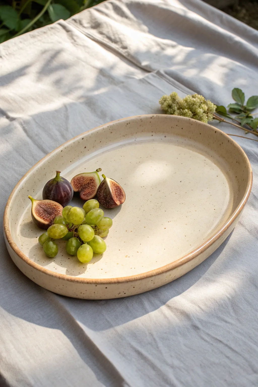 Classic oval slab platter in a soft neutral glaze, styled simply with fruit for scale.