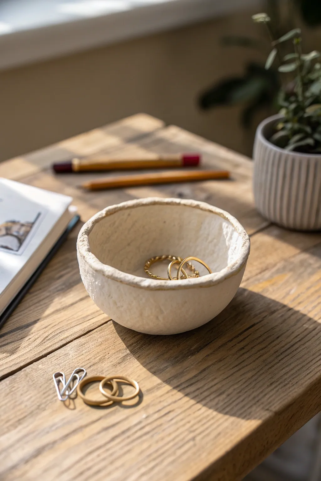 Beginner pinch pot trinket bowl with cozy handmade rim, perfect for rings on a wooden table.