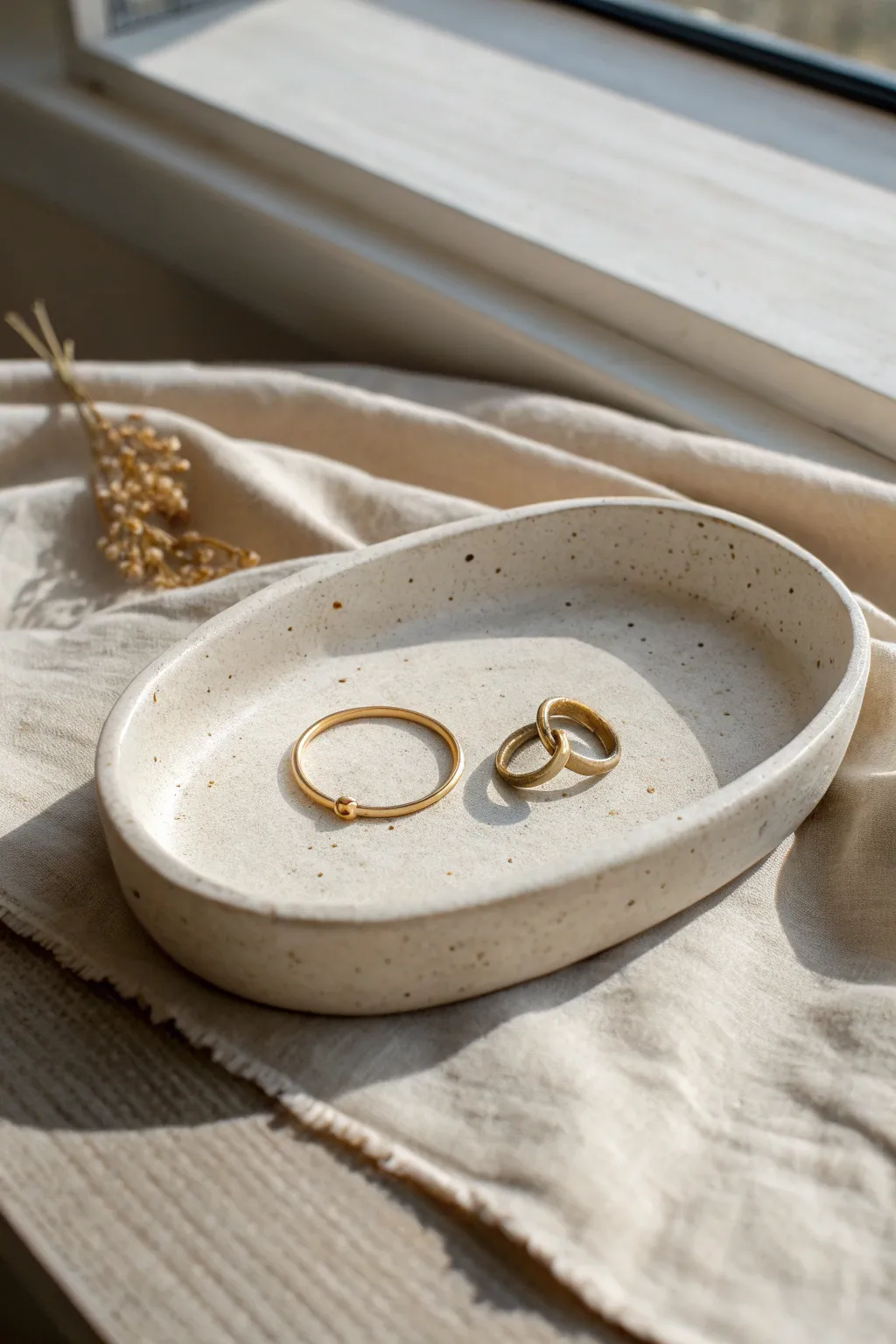 Minimal oval clay catchall tray in warm off-white, styled with rings and a key on linen.
