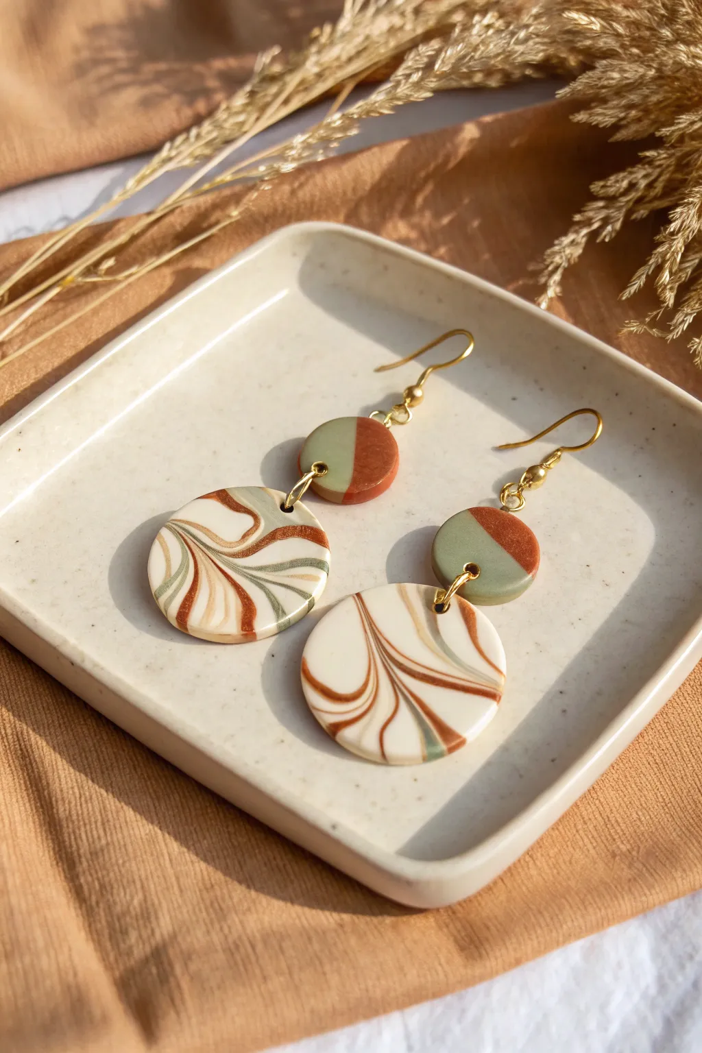 Bold marbled polymer clay statement earrings in earthy tones, styled in soft Scandinavian light