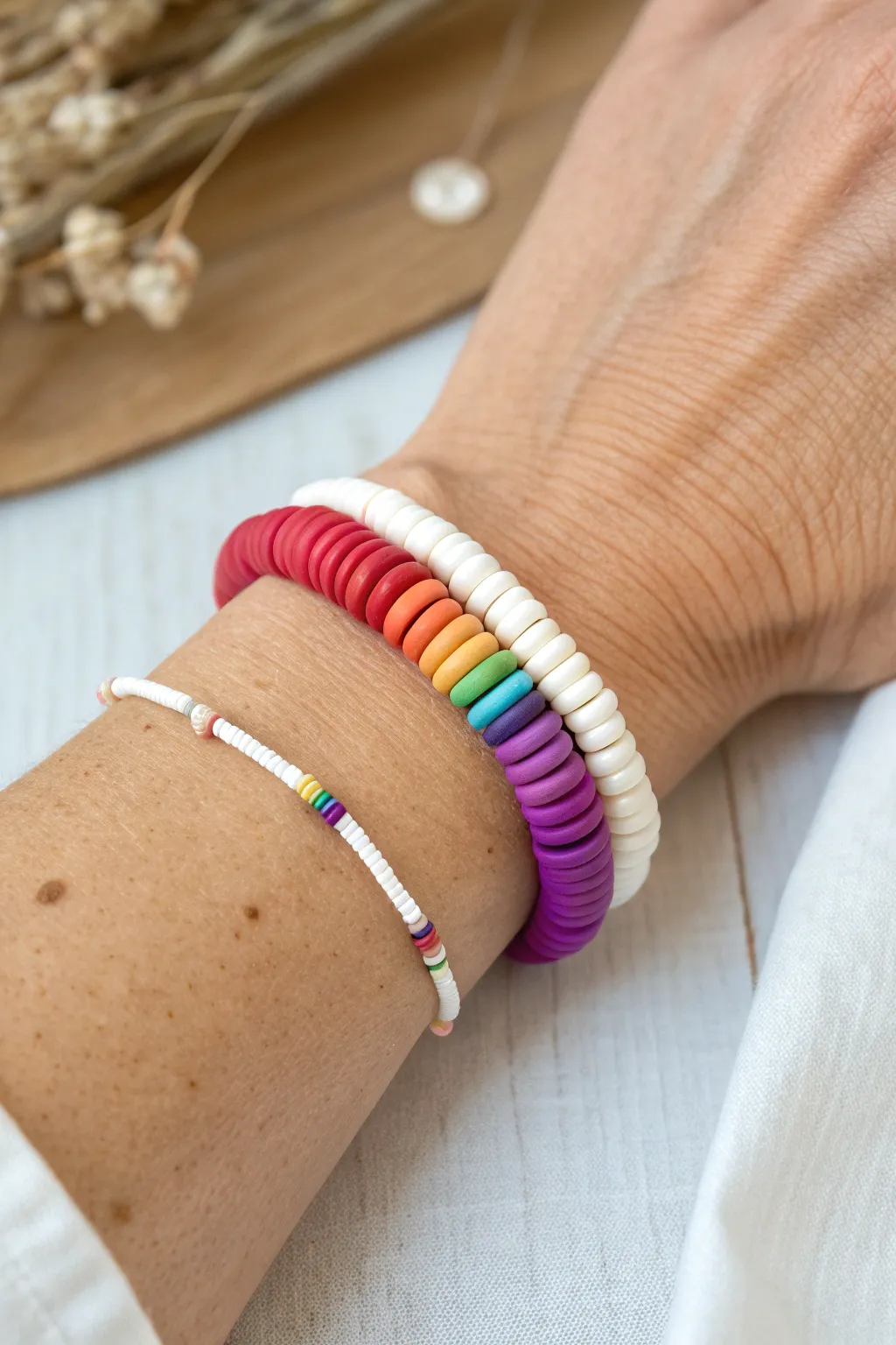 Classic rainbow heishi bracelet, clean color order on wrist with a minimalist white companion.