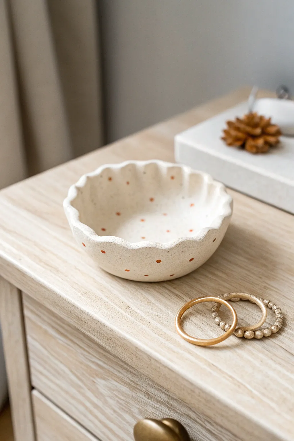 Classic pinch pot trinket dish with soft scalloped edges, styled simply for a calm nightstand moment.