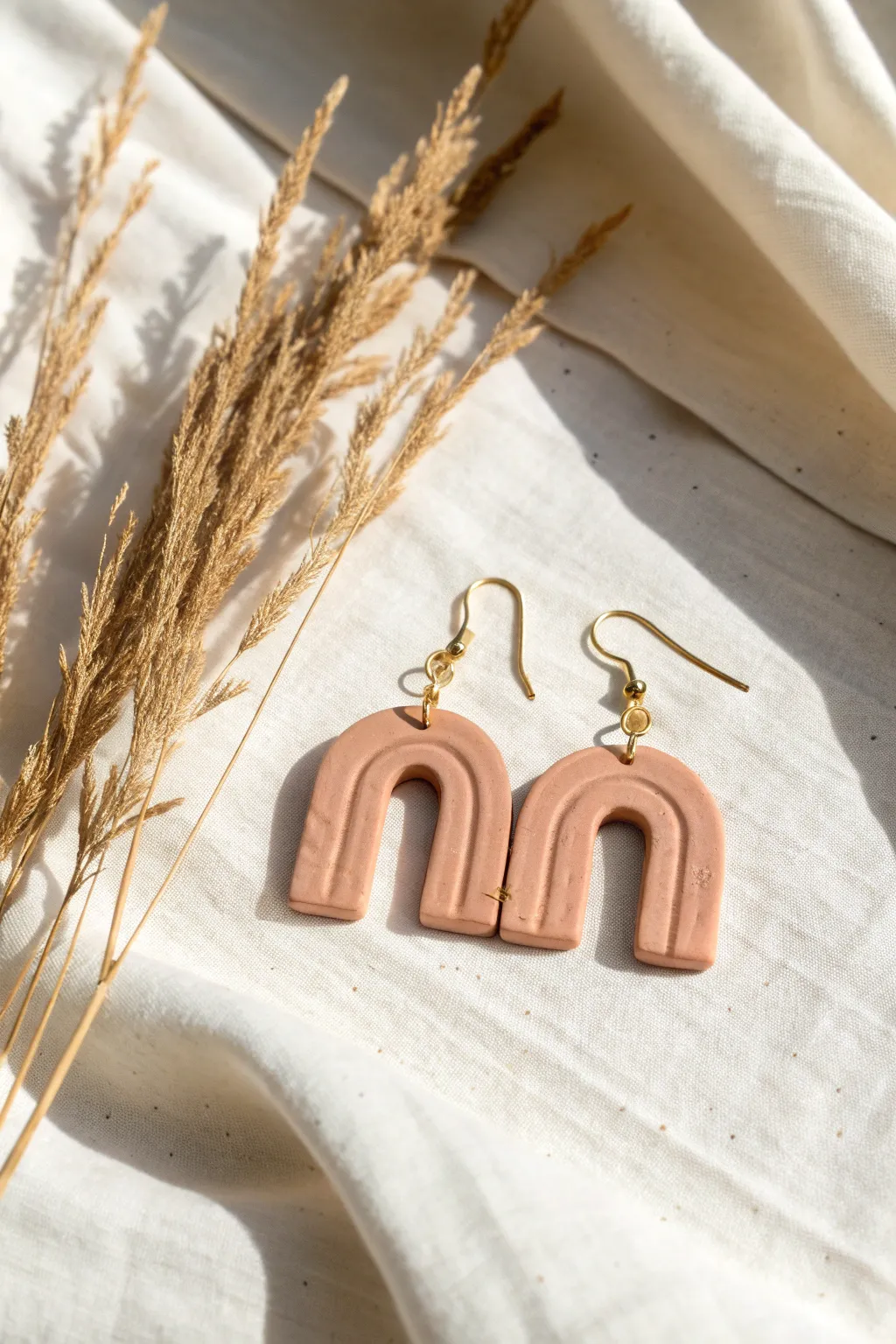 Classic arch clay dangles in soft neutral matte finish, minimalist flat-lay for easy DIY inspo.