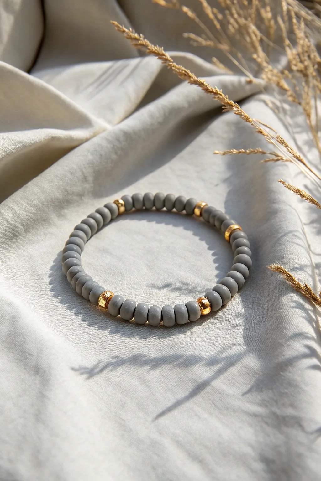 Minimal matte grey heishi bracelet accented with tiny gold spacers on soft linen.
