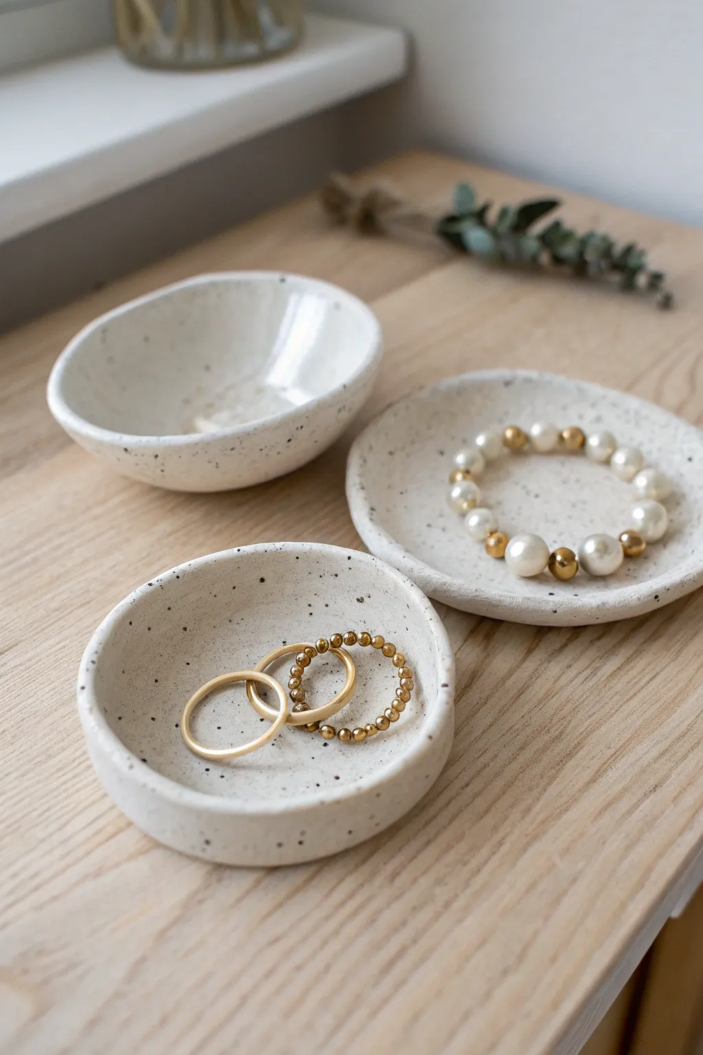 Mini handmade clay trinket dishes in simple shapes, styled with rings and beads on light wood.