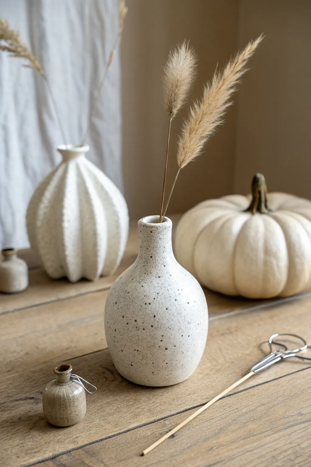 Three mini bud vases, one stem each, plus a paperclip for scale in calm Nordic boho light.