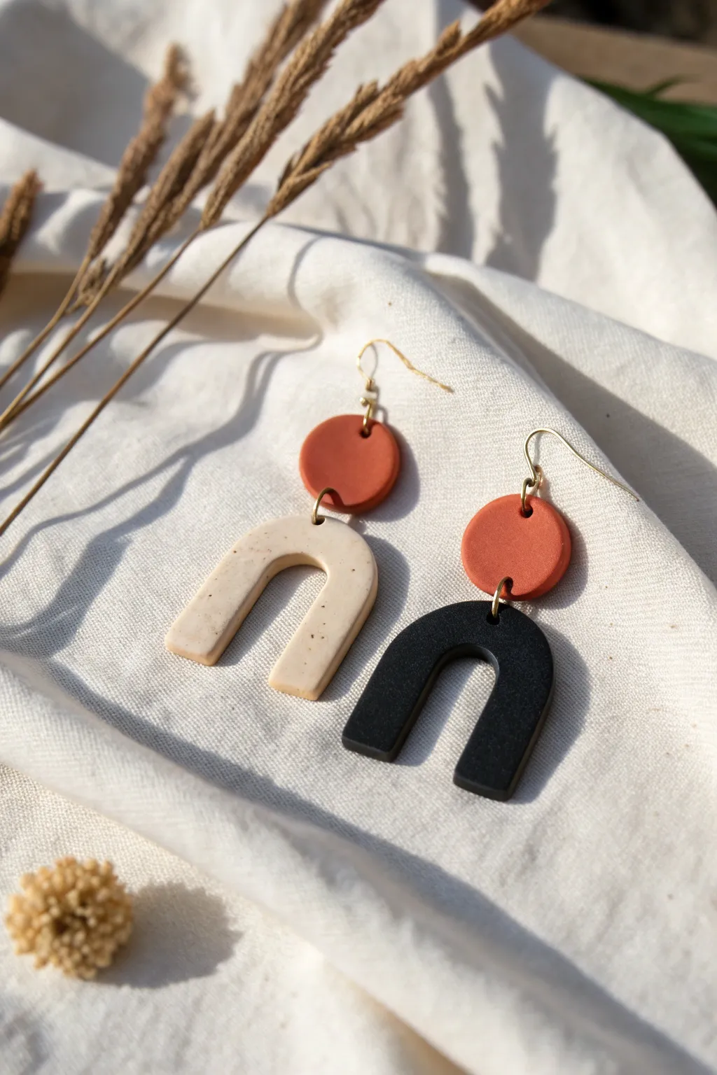 Minimal statement polymer clay earrings in arches and circles, matte neutrals on linen.