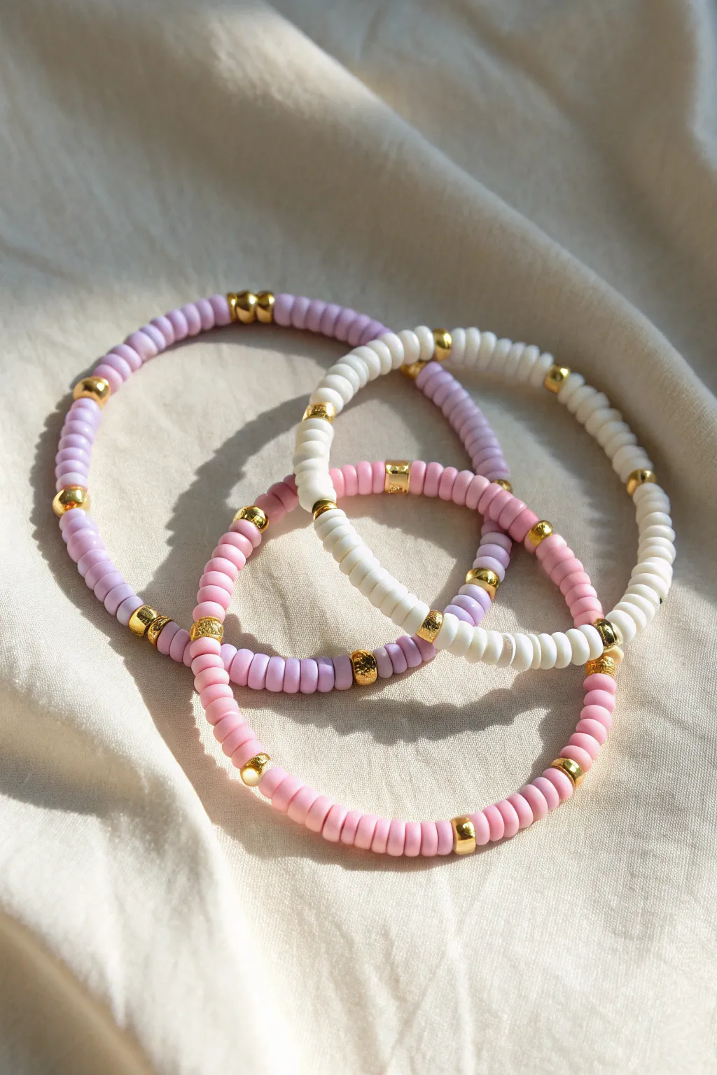 Hot pink, lavender, and white heishi stack with evenly spaced gold spacers for a clean preppy look