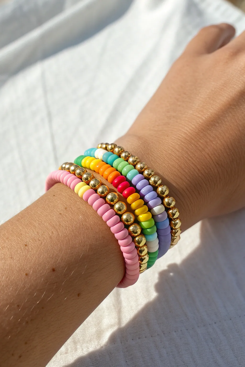 Classic rainbow clay disc stack with gold spacers for a preppy, sunny wrist moment.