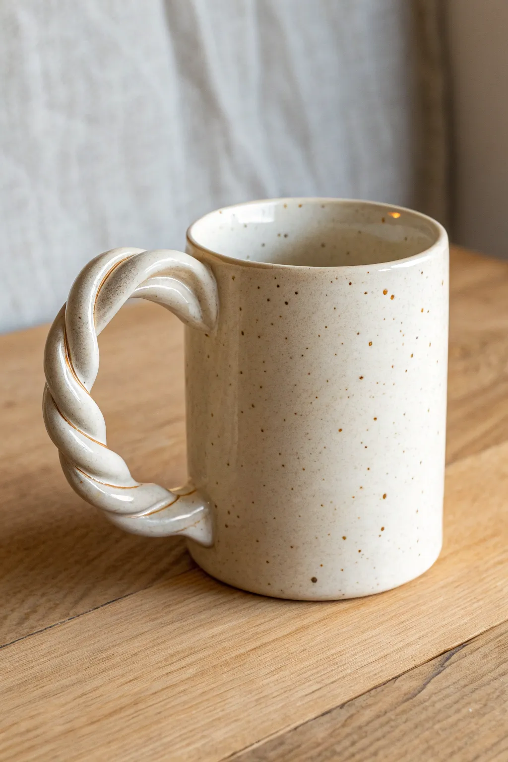 Glossy sculptural-handle mug on warm wood, minimalist and handmade with bold, twisty charm