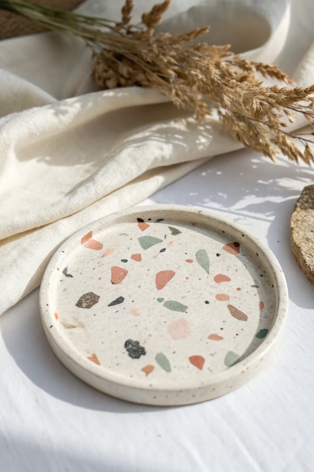 Terrazzo-speckled air-dry clay coaster with soft boho tones on a crisp minimalist backdrop.
