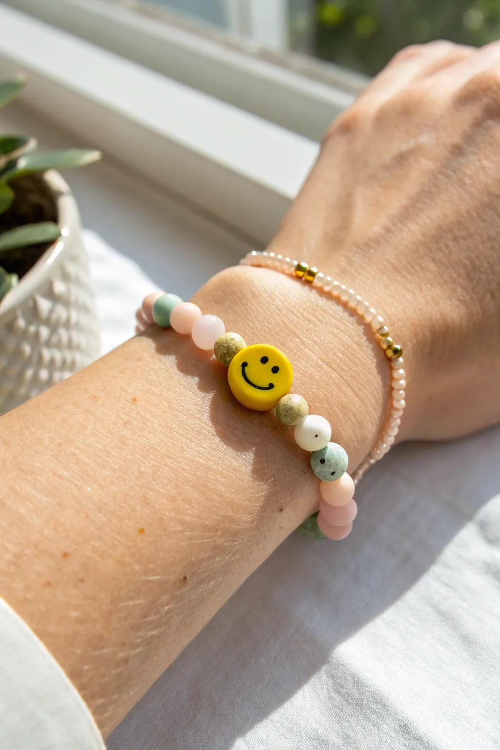 Center smiley focal bead with soft pastel clay beads in a clean Scandinavian boho bracelet look.