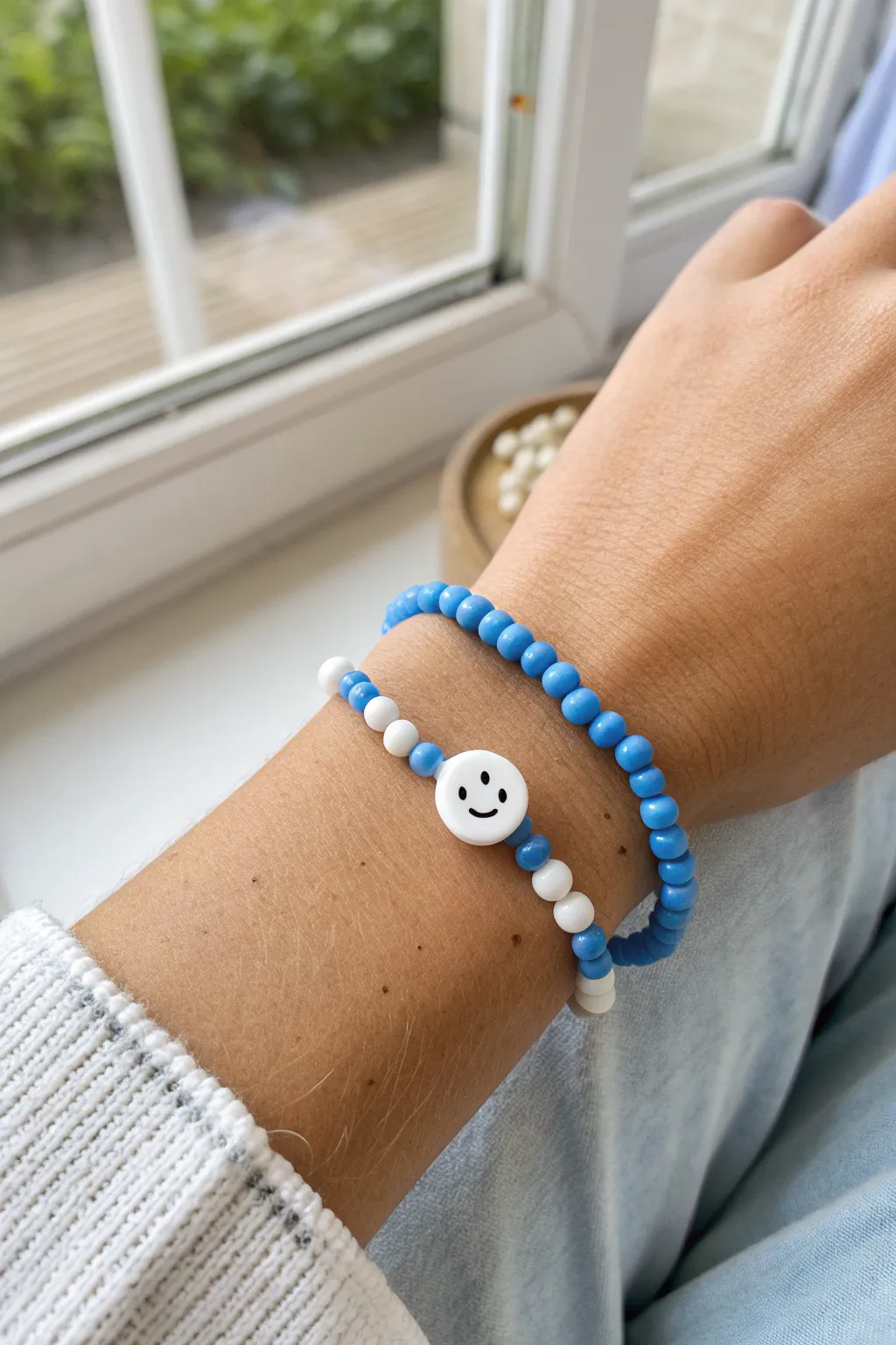 Preppy blue and white heishi bracelet with a cheerful smiley bead, clean and playful.