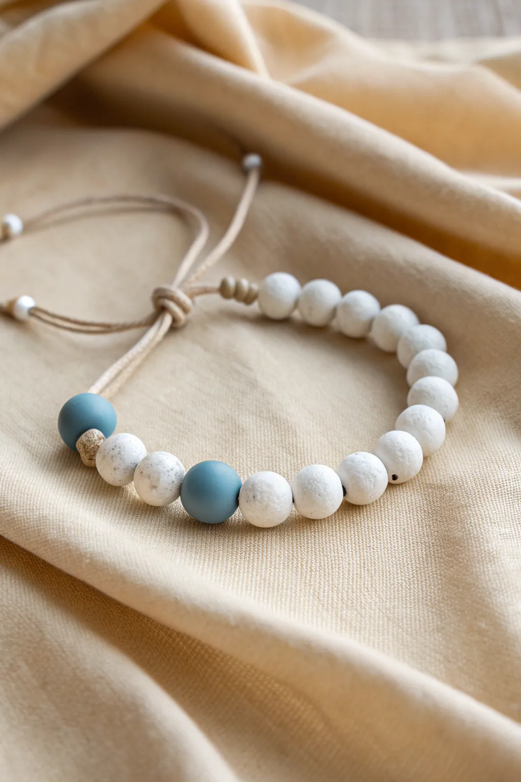 Micro-pattern clay bead bracelet in crisp white and dusty blue, calm Scandinavian rhythm.