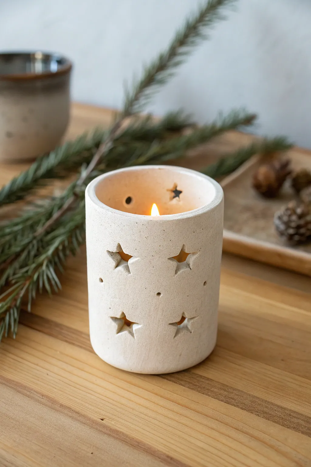 Minimal clay tea light holder with star cutouts, warm glow and cozy Scandinavian Christmas vibe