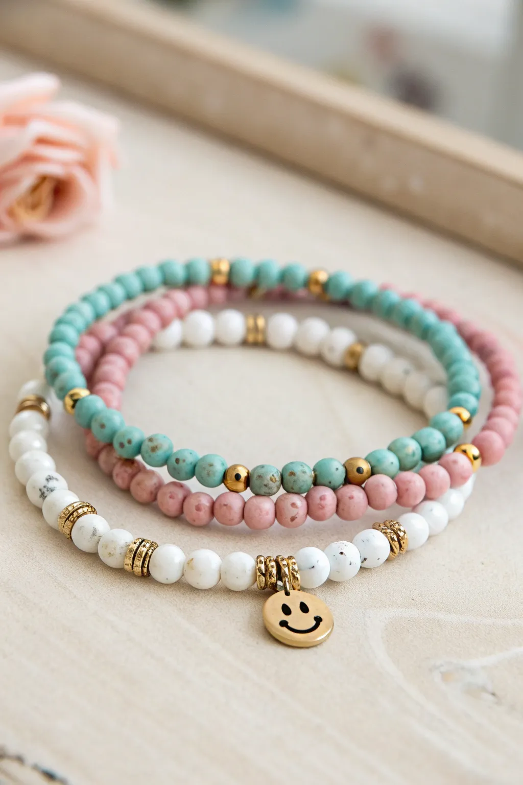 Tiny smiley accent clay bead bracelet stack in teal pink and white for a clean minimalist look.
