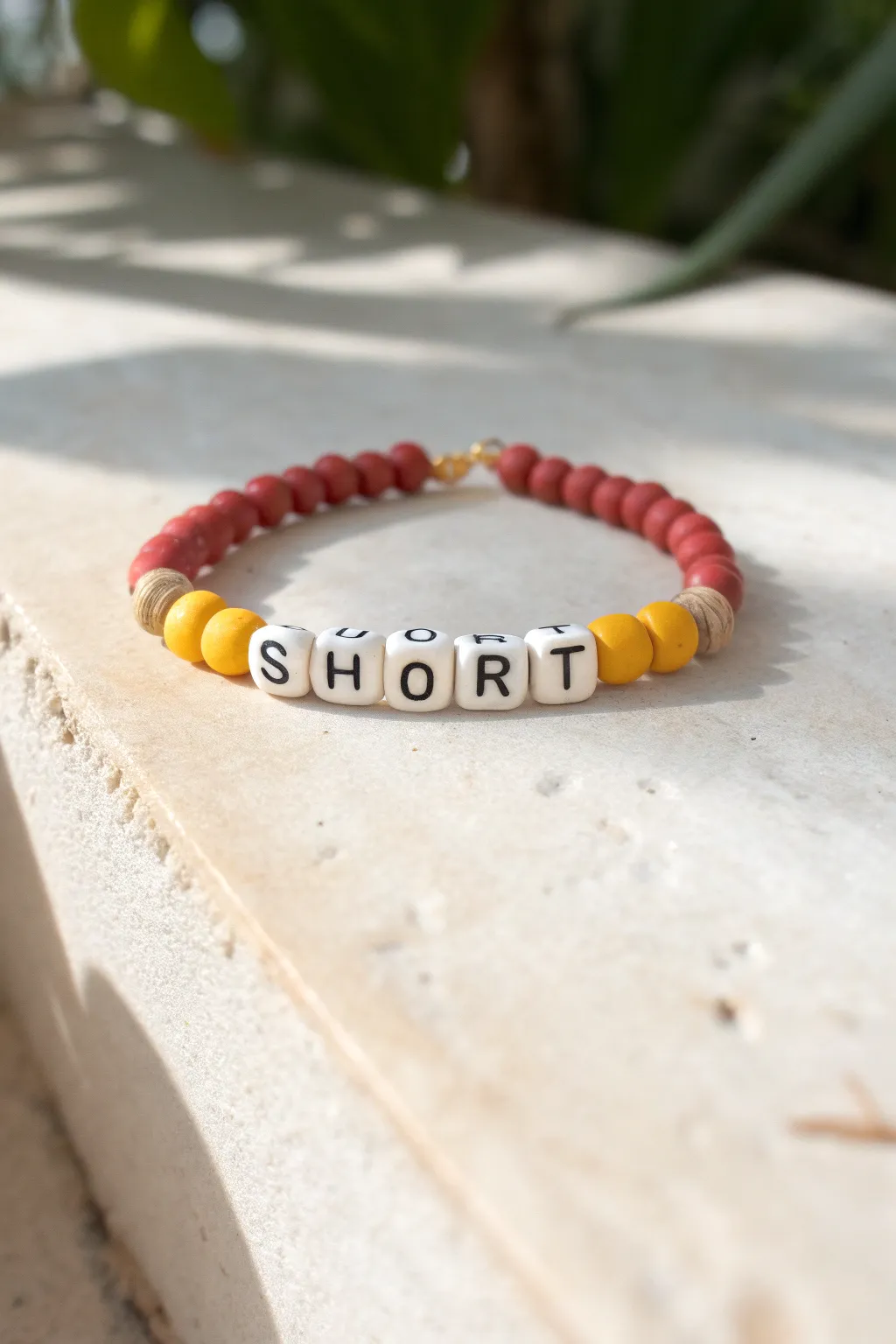 School-color clay bracelet flat lay with simple letter beads, minimalist spirit accessory idea.