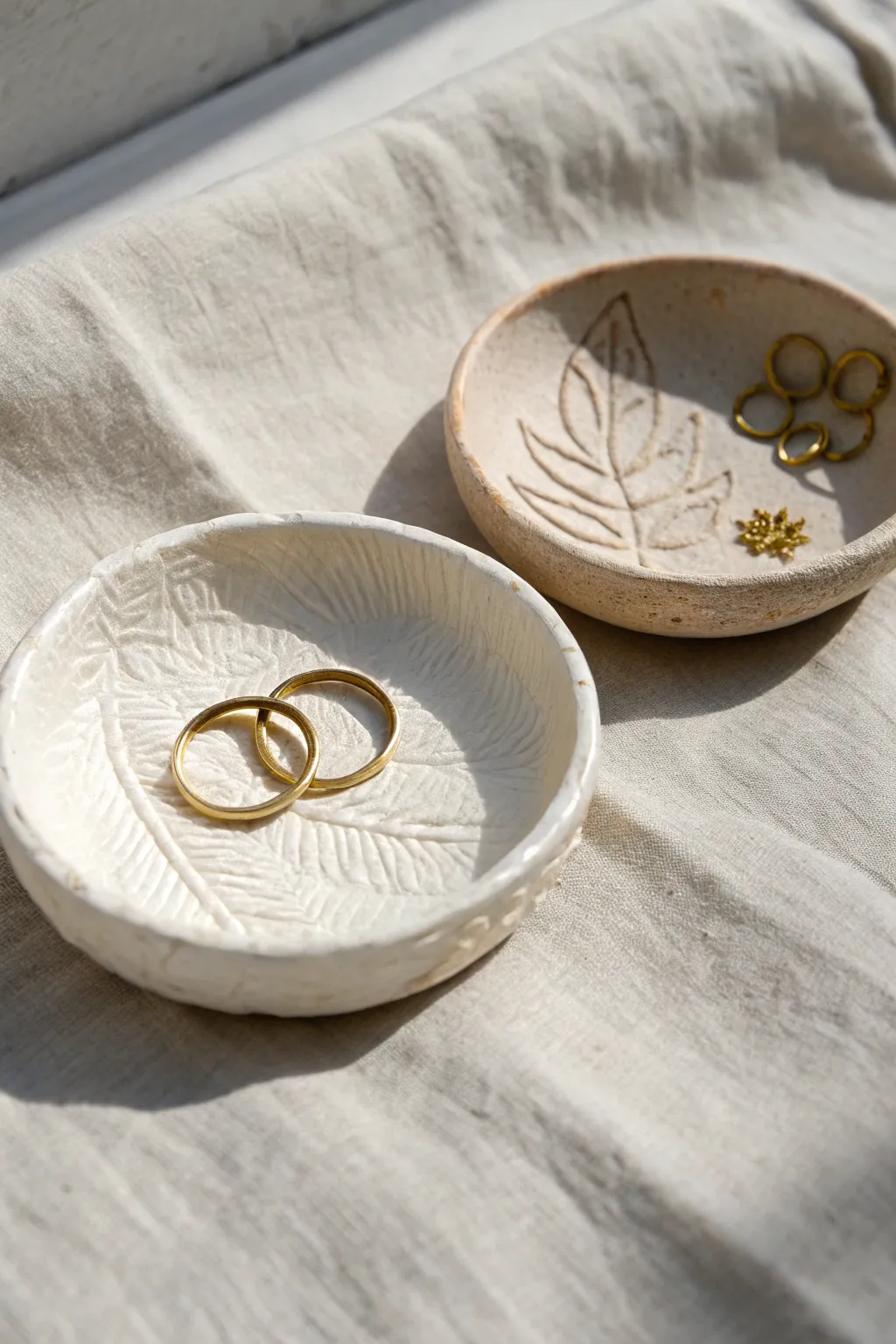 Two easy stamped clay ring dishes with matte finish textures, styled simply with gold rings.