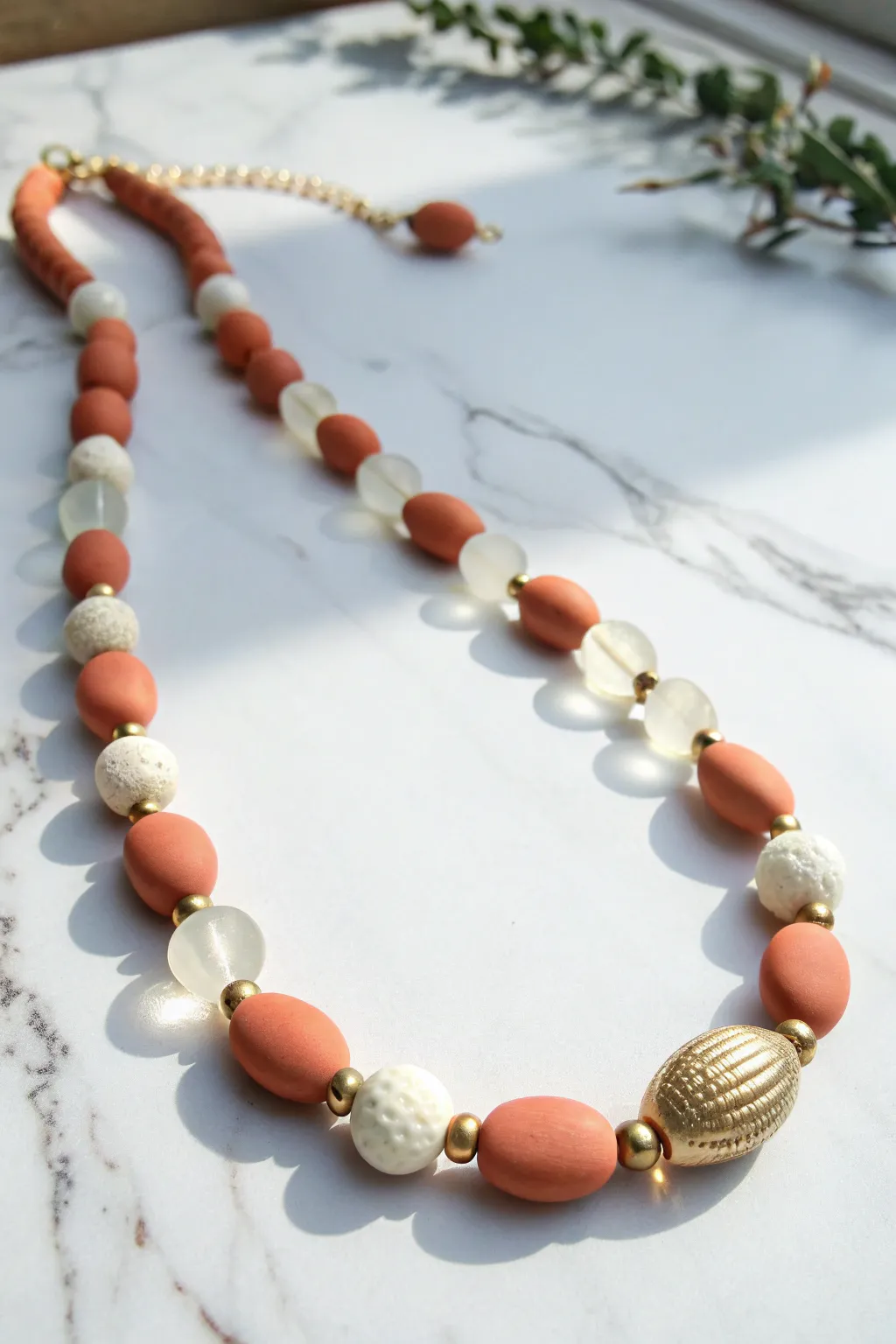 Minimal mixed bead and clay necklace flat lay on marble, soft boho tones with crisp contrast.