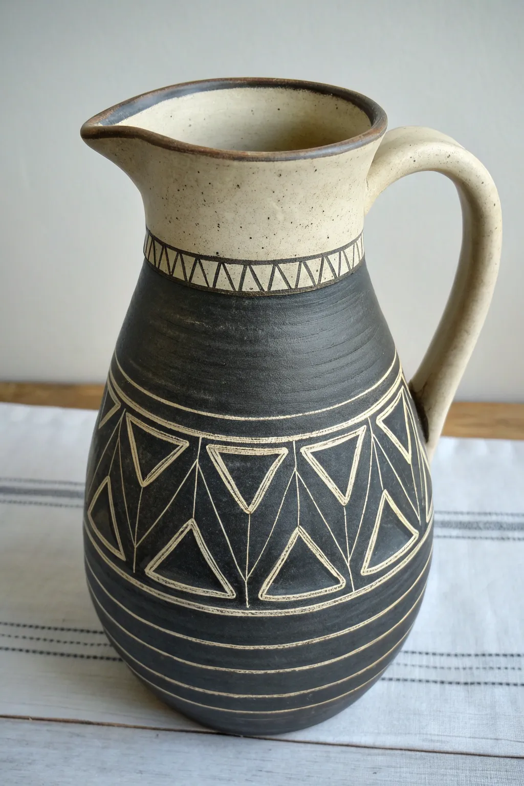 Bold sgraffito pitcher in dark clay and light slip, clean lines and cozy minimalist charm