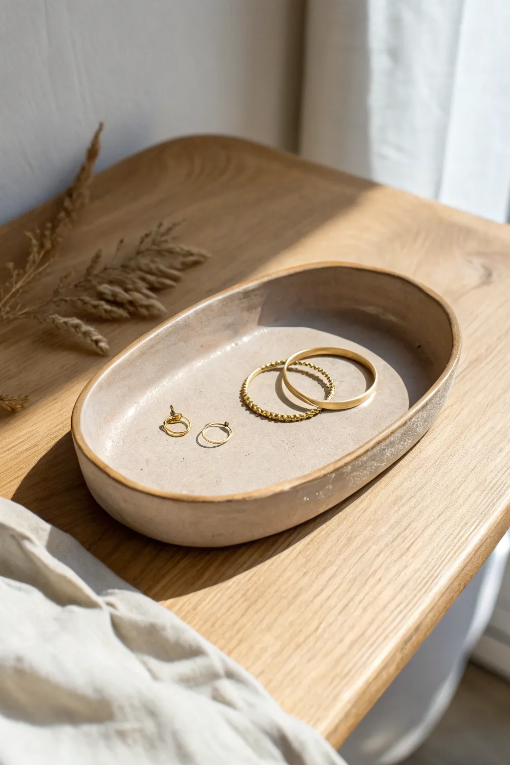 Minimal matte clay tray with a delicate gold rim, styled with rings in warm, airy light
