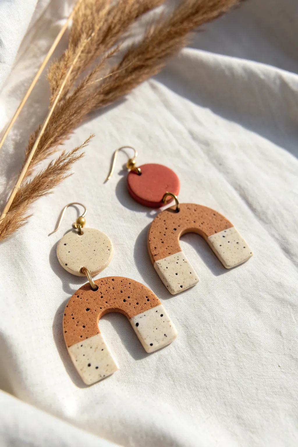 Abstract polymer clay earrings in terracotta and cream, minimal shapes with speckled detail.