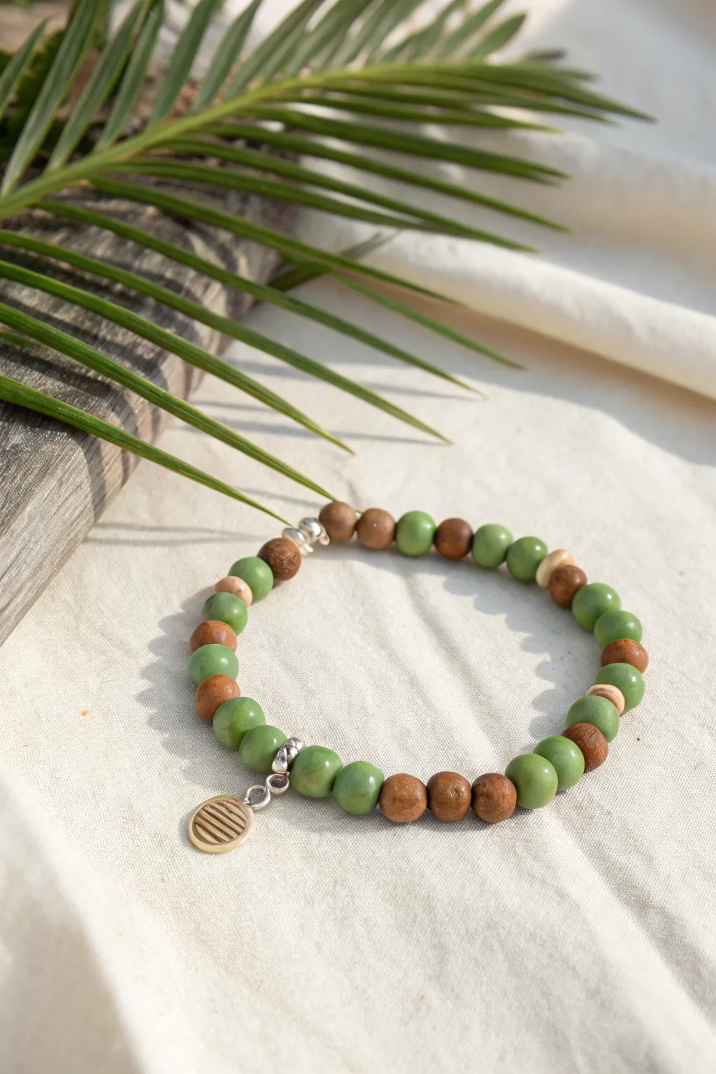 Palm greens meet coconut browns in a minimalist beachy clay bead bracelet with a soft neutral charm.