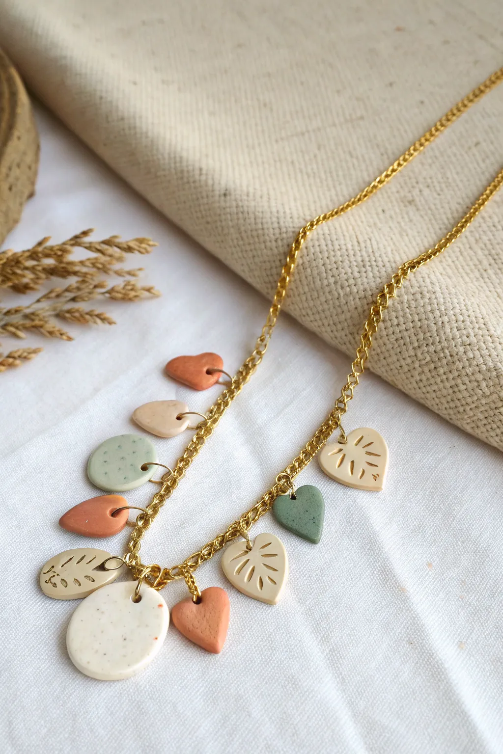 Air-dry clay statement necklace charms in warm neutrals with a sage accent, minimal and handmade.