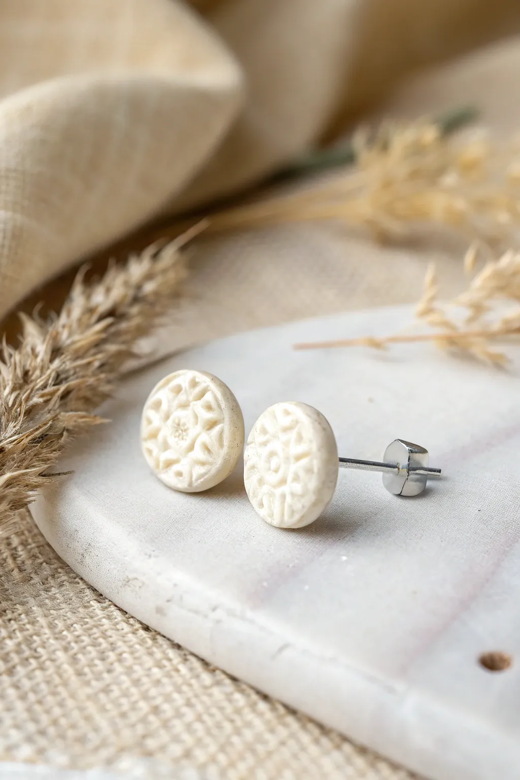 Minimal stamped texture stud in soft monochrome tones, crisp shadows, cozy Scandinavian boho vibe