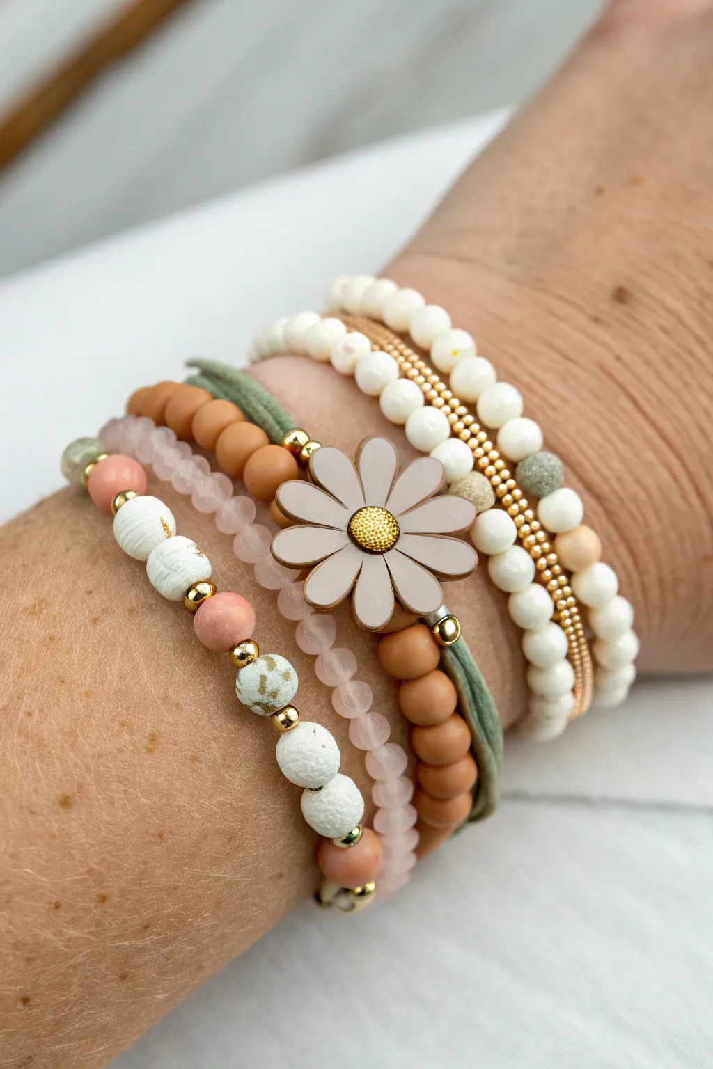 Stackable bracelet set with one flower focal bead and four simple heishi bands in soft neutrals