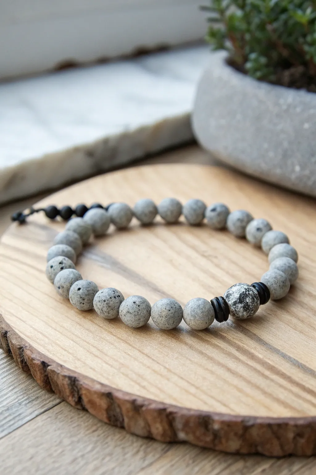 Concrete-speckle grey clay bead bracelet with matte black spacers, minimal industrial charm.