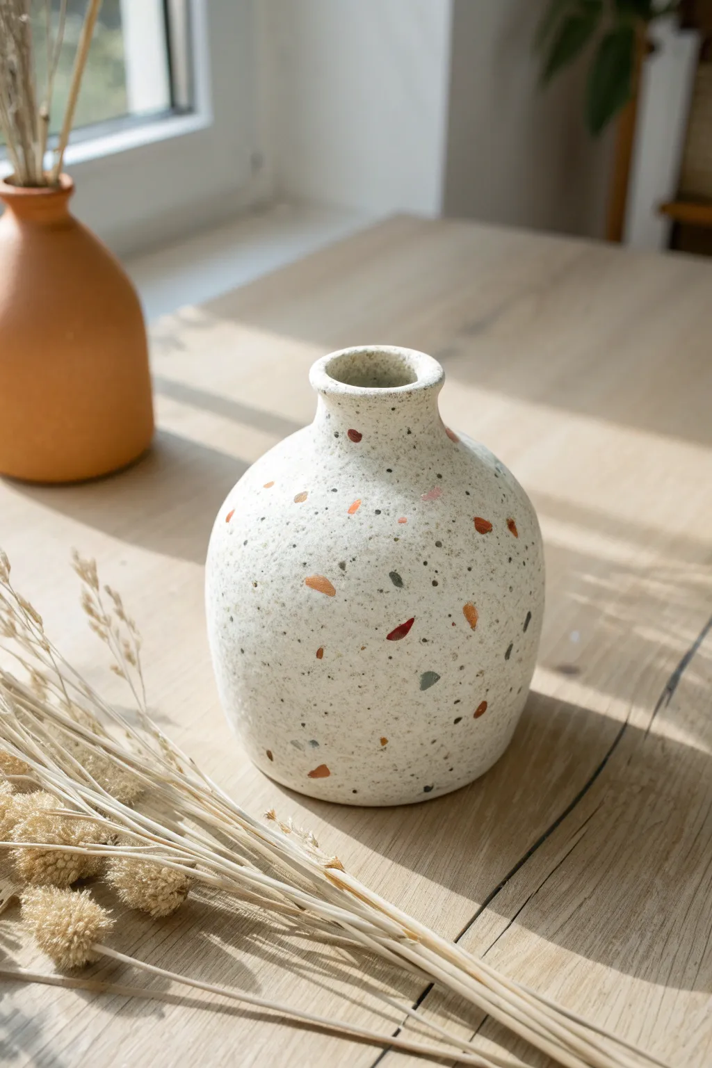 Terrazzo-speckled handmade clay vase with minimal dried florals in soft Scandinavian light.