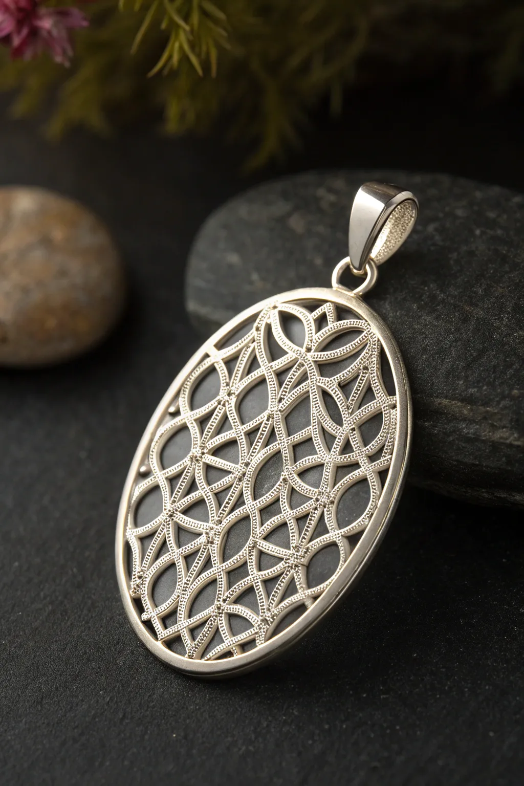Airy syringe filigree metal clay pendant in matte silver, glowing against a dark backdrop.