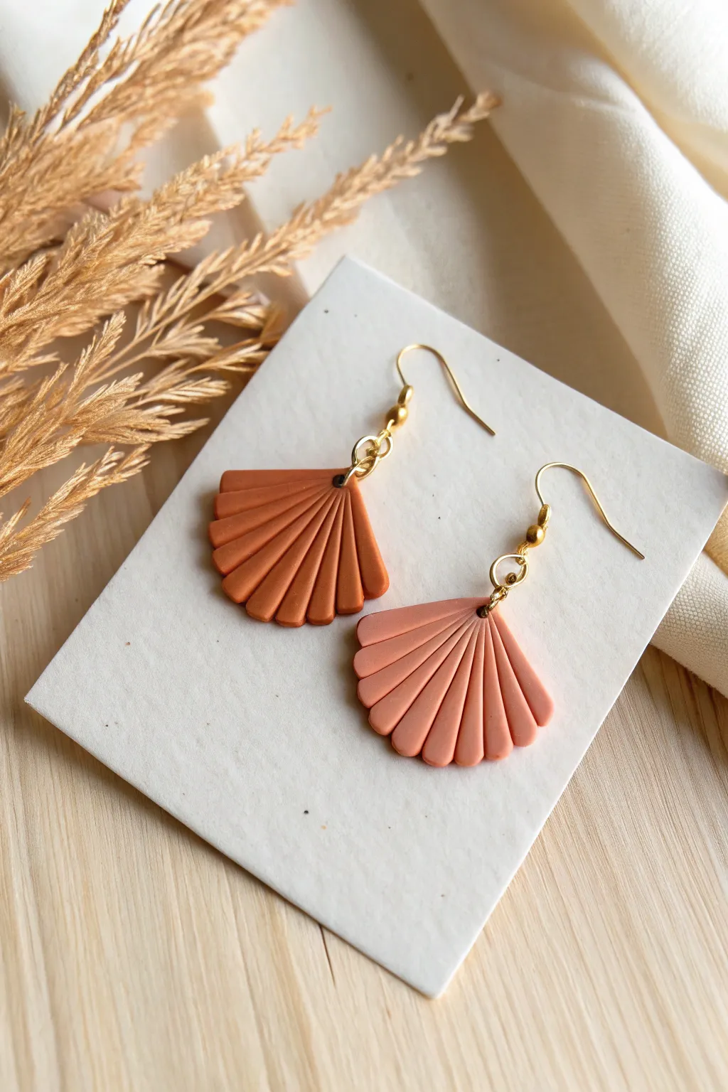 Scalloped fan polymer clay dangles in two soft tones, minimalist display for modern boho style.