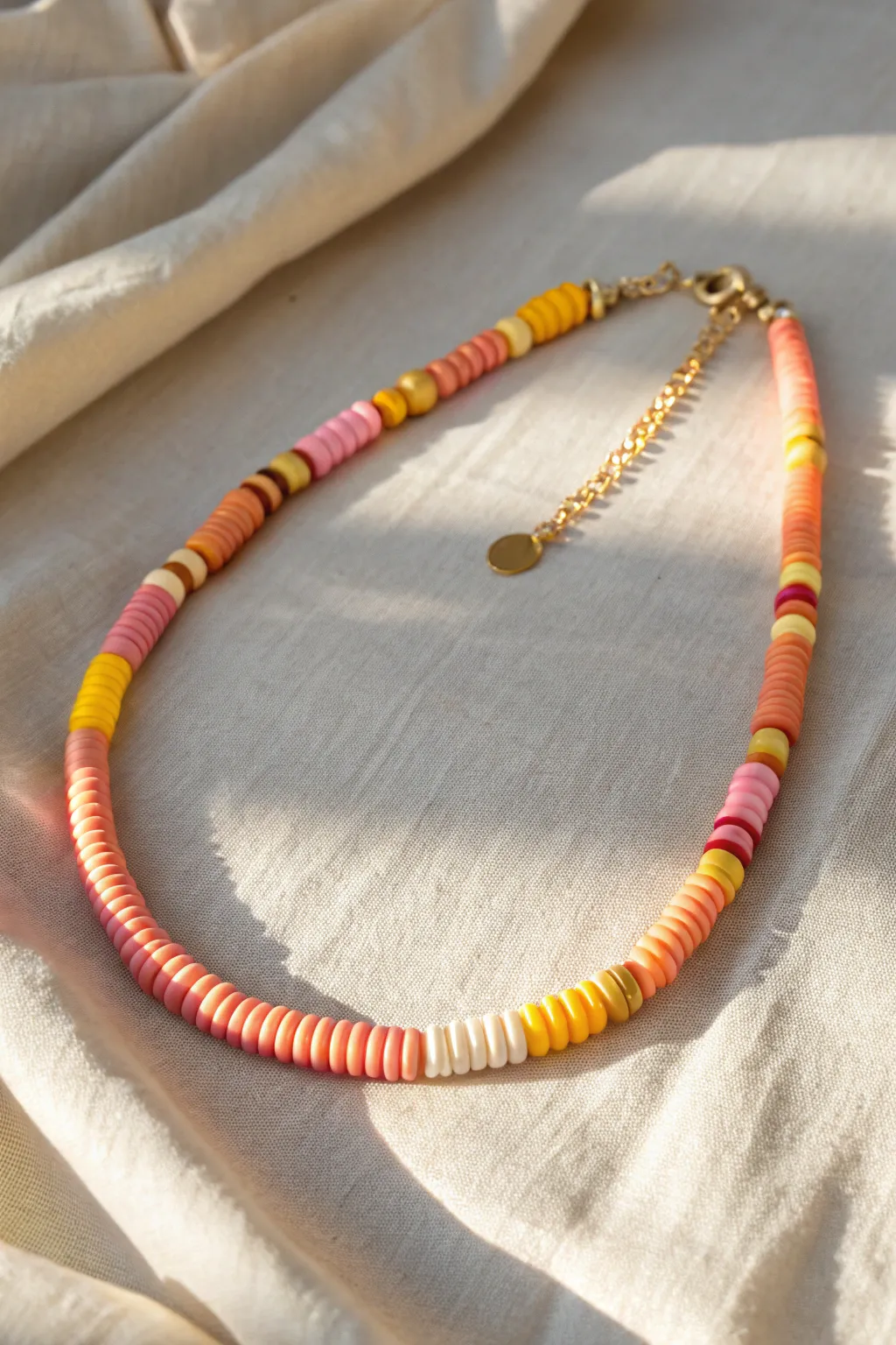 Sunset sorbet heishi necklace in coral, tangerine, lemon, and pink on sunlit linen