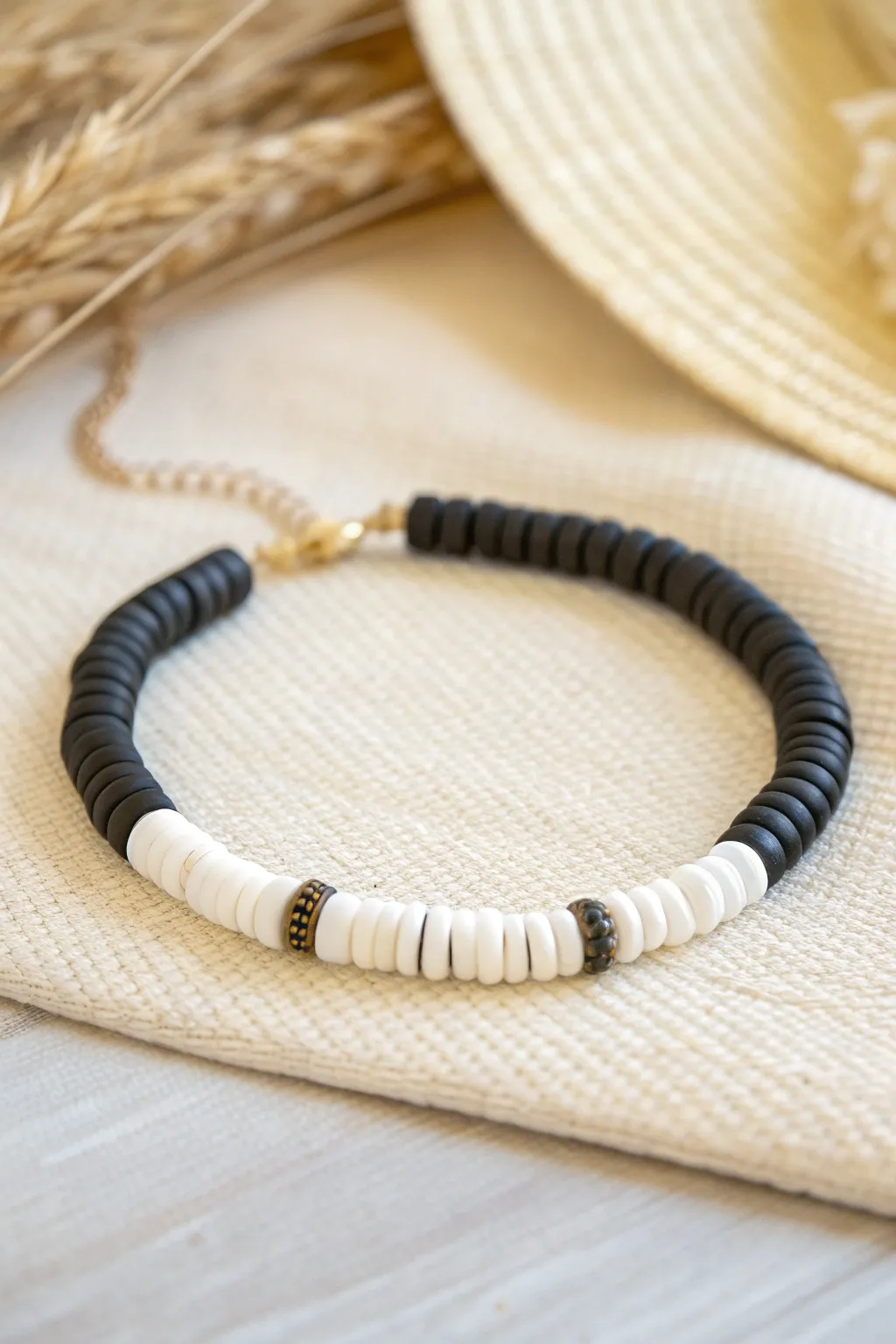 Bold black-and-white heishi clay bead bracelet on linen for a clean, graphic minimalist look