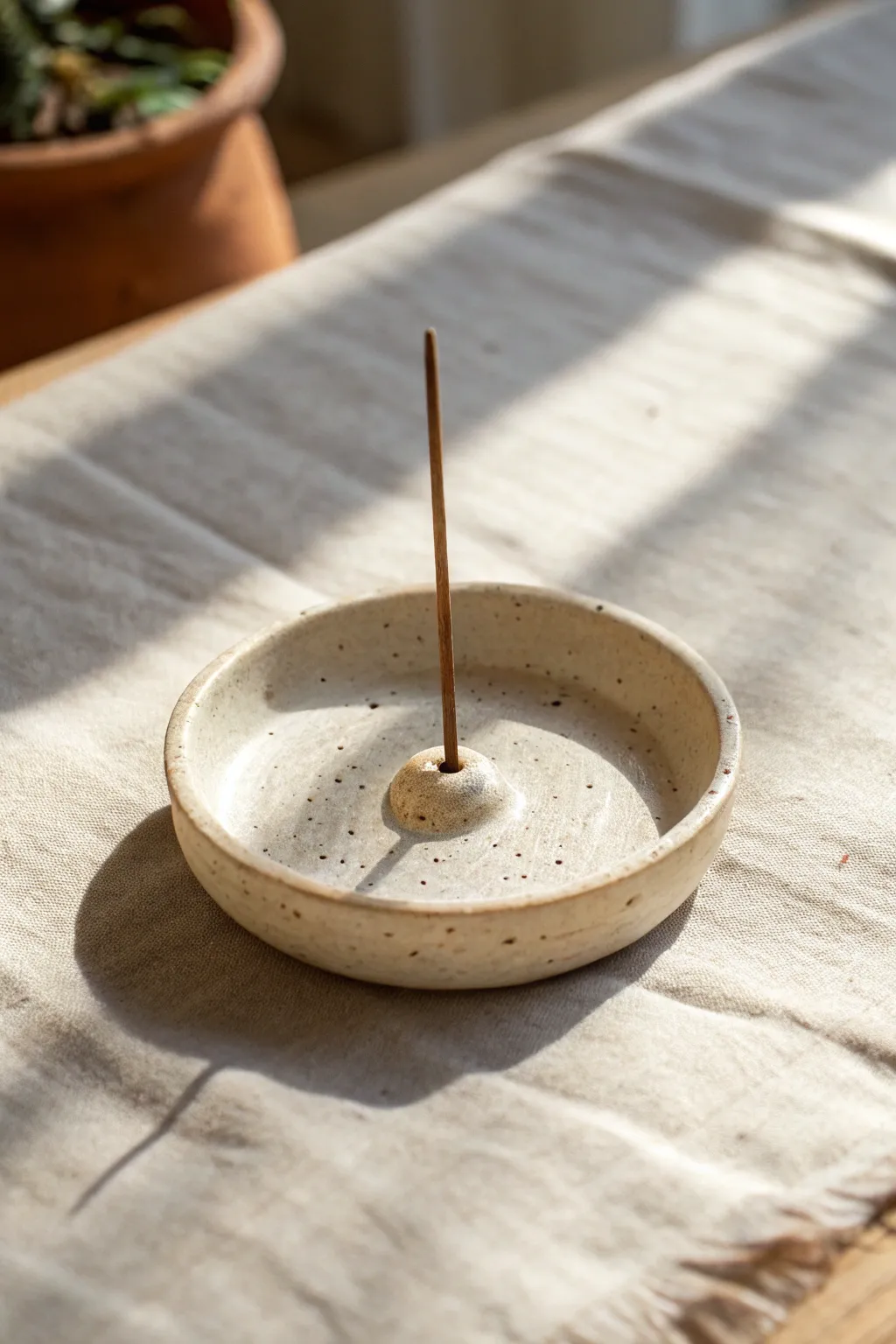 Tiny minimalist clay incense holder with a clean center hole in soft, calming natural light.