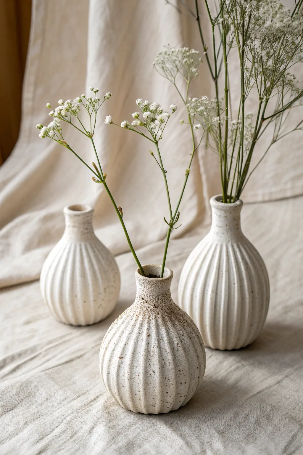 Three mini wrapped-slab bud vases with single blooms, an easy soft slab set for any shelf.