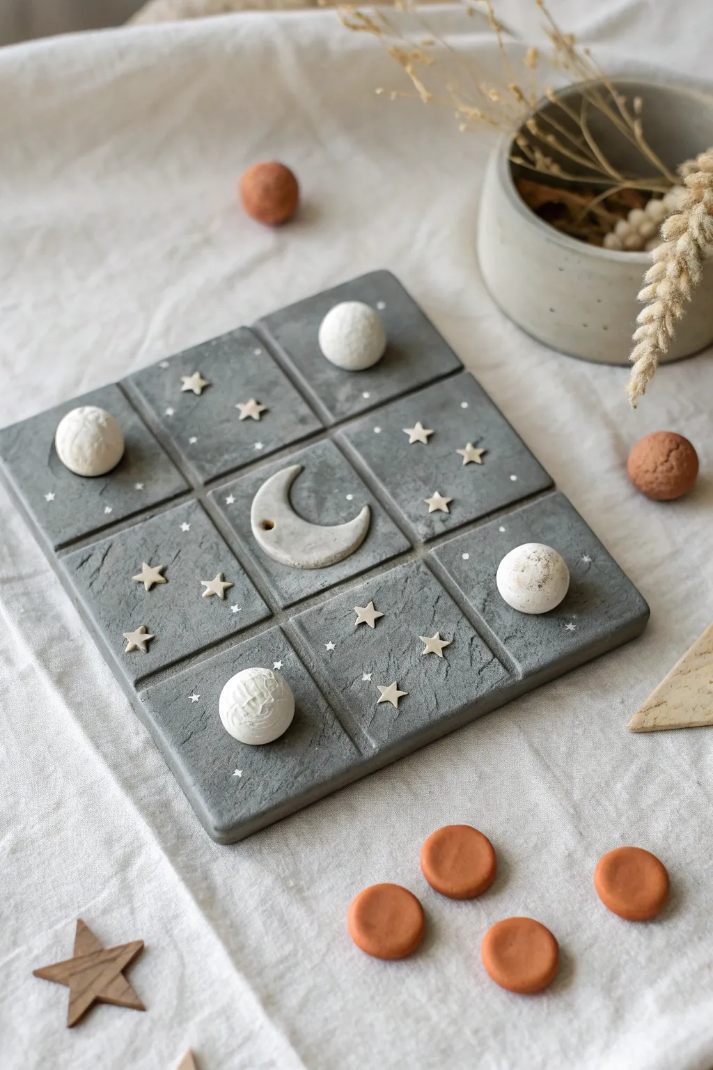 Moon crater clay tic tac toe with tiny planet and rocket tokens in calm minimalist tones